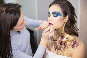 a artista aplica-se Maquiagem para uma atraente jovem modelo foto