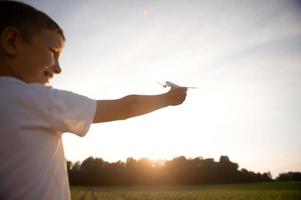 uma Garoto detém uma brinquedo avião dentro dele mãos. lançamento para dentro a céu foto