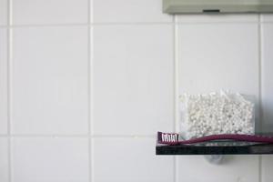 escova de dente e algodão cotonetes estão em a estante dentro a banheiro foto