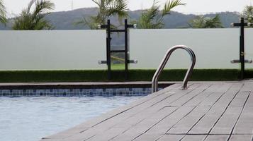 natação piscina mão trilho ou escada escada para Socorro pegue dentro ou pegue Fora do a piscina. lindo Beira do a natação piscina com uma de madeira área coberta. foto