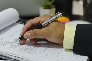 um empresário segurando uma caneta em documentos comerciais foto