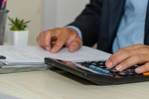 um empresário olhando documentos comerciais e trabalhando em uma calculadora trabalhando em casa foto