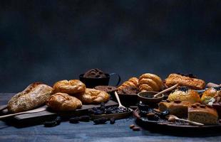 vista superior pão fresco passas marrom gergelim padaria feita de farinha de trigo comida caseira adequada para uma alimentação saudável no chão de mesa de madeira preto rústico fundo escuro foto