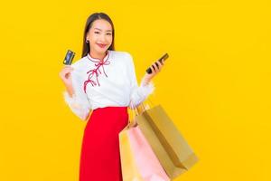 jovem mulher asiática com cartão de crédito e sacola de compras