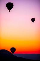 balão de ar quente voando sobre paisagens rochosas na Capadócia com lindo céu no fundo foto