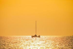 barco na água com um pôr do sol laranja foto