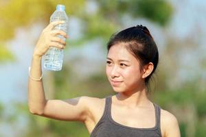 mulher esportiva bebendo água em um dia ensolarado foto
