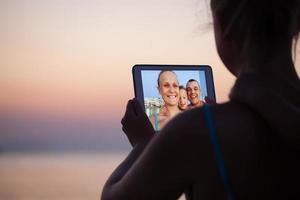 família conectando-se virtualmente em uma praia foto