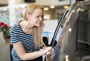 mulher admirando um carro em um salão de automóveis foto