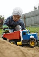 menino brincando com um caminhão de brinquedo lá fora foto