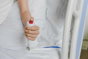 close-up da mão do paciente pressionando o botão de emergência