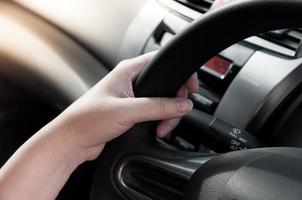 mulher mão segurando em Preto direção roda, mulher dirigir uma carro foto