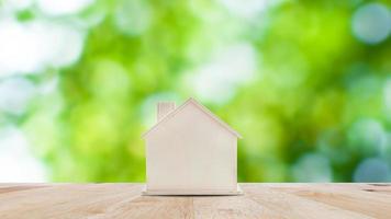 pequeno casa modelo em de madeira mesa com natureza verde bokeh abstrato fundo. família vida e o negócio real Estado conceito. foto