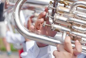 humano mão jogando a flugelhorn, fragmento do tuba com mãos do músico foto