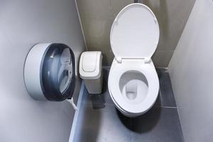 vaso sanitário em um banheiro moderno com lixeiras e papel higiênico, banheiro limpo com descarga foto