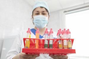 o médico assistente de laboratório segura tubos de ensaio com análises nas mãos. foto