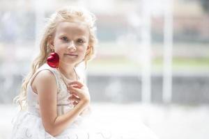 pequeno menina segurando uma pequeno vermelho coração. criança com uma brinquedo coração. foto