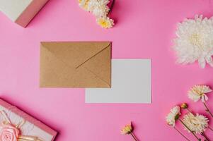 Castanho envelope e cartão com presente caixa em Rosa fundo decorado com flores foto