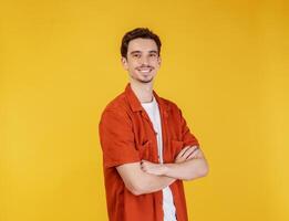 retrato de jovem bonito em pé com os braços cruzados com isolado no fundo amarelo do estúdio foto