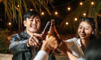retrato de amigos asiáticos felizes jantando juntos - jovens sentados na mesa do bar brindando ao jantar com copos de cerveja ao ar livre - pessoas, comida, estilo de vida de bebida, conceito de celebração de ano novo. foto