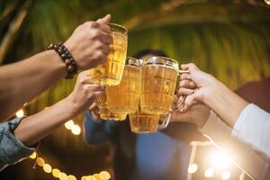 retrato de amigos asiáticos felizes jantando juntos - jovens brindando copos de cerveja jantar ao ar livre - pessoas, comida, estilo de vida de bebida, conceito de celebração de ano novo. foto