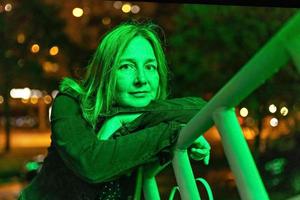 retrato de uma jovem em uma cidade noturna em verde neon em uma noite de verão. luzes da cidade foto