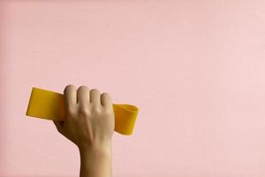 mulher mão com amarelo Esportes fita em Rosa fundo foto