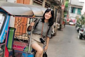 jovem ásia mulher mochila viajante em pé uma lado do tuk tuk Táxi em verão Férias às Bangkok, tailândia. foto