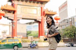 jovem ásia mulher mochila viajante desfrutando China Cidade rua Comida mercado dentro Bangkok, tailândia. viajante verificação Fora lado ruas. foto