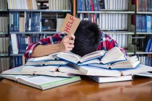 ásia masculino alunos estão cansado e estressado com lendo uma muitos para preparar para a exame. foto