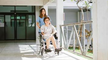 fisioterapeuta sorridente cuidando do paciente sênior feliz em cadeira de rodas foto