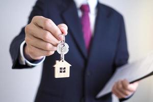 casa vendas agentes estão dando casa chaves para Novo proprietários. senhores da terra e casa chaves conceito foto