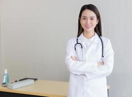 médico jovem bela mulher asiática em pé com os braços cruzados foto