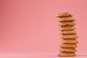 biscoitos de aveia com chocolate são empilhados em um fundo rosa. foto