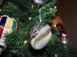 bola de natal de vidro feita à mão no detalhe da árvore de natal luzes desfocadas foto