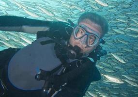 retrato de mergulhador enquanto mergulhava dentro de um cardume de peixes debaixo d'água foto