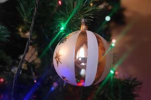 bola de natal de vidro feita à mão no detalhe da árvore de natal luzes desfocadas foto
