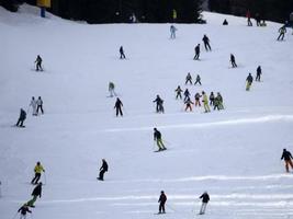 muitos esquiadores esquiando nas montanhas de neve do vale das dolomitas gardena foto