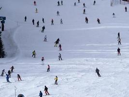 muitos esquiadores esquiando nas montanhas de neve do vale das dolomitas gardena foto