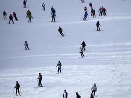 muitos esquiadores esquiando nas montanhas de neve do vale das dolomitas gardena foto