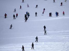 muitos esquiadores esquiando nas montanhas de neve do vale das dolomitas gardena foto