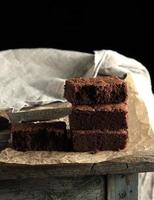 pilha de pedaços quadrados assados de bolo de brownie de chocolate em papel manteiga marrom foto