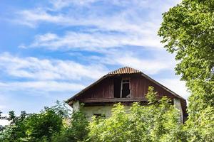 linda e velha casa de fazenda abandonada na zona rural em fundo natural foto