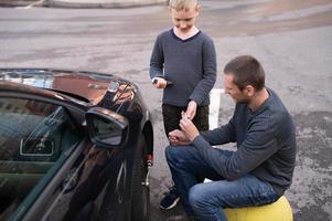 fofa Garoto ajuda Papai consertar a carro. desparafusar a roda foto