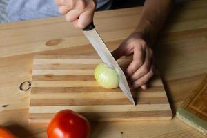 masculino mãos cortar cebolas em uma de madeira borda foto