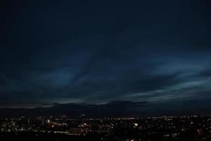 Sombrio azul nuvem com branco luz céu fundo e cidade luz meia noite tarde Tempo foto