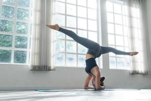 ásia mulher praticando ioga em pé dentro headstand às ginástica estúdio foto