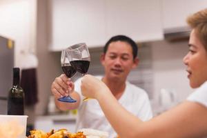 doce casal tendo jantar com brindar óculos do vermelho vinho às lar. foto