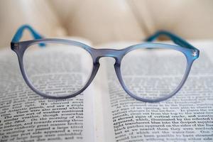 óculos de leitura azul claro isolados em um livro foto