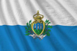 bandeira de san marino com grandes dobras acenando de perto sob a luz do estúdio dentro de casa. os símbolos oficiais e cores no banner foto